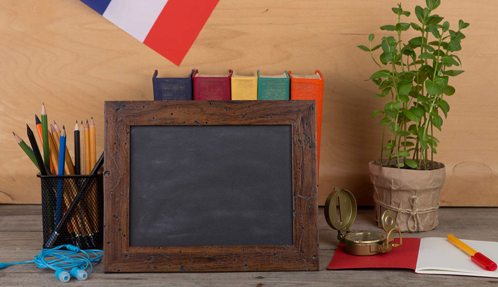 Learning french language concept – blank blackboard, flag of the France, books, pencils, compass