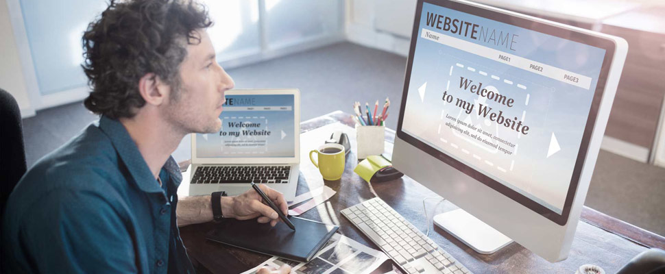 Composite image of build website interface against photographer working on his computer