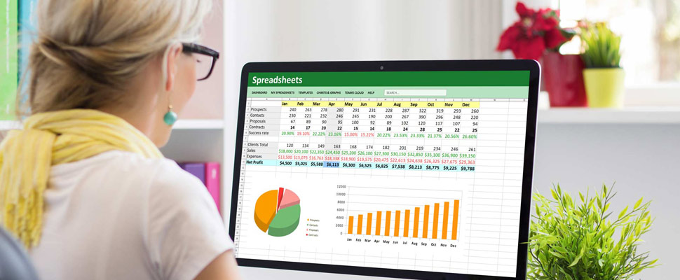 Woman working with data and graphs in spreadsheet document on de Woman working with data and graphs in spreadsheet document on de