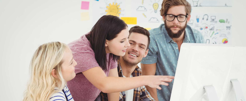 Business professionals discussing at computer desk in office Business professionals discussing at computer desk in office